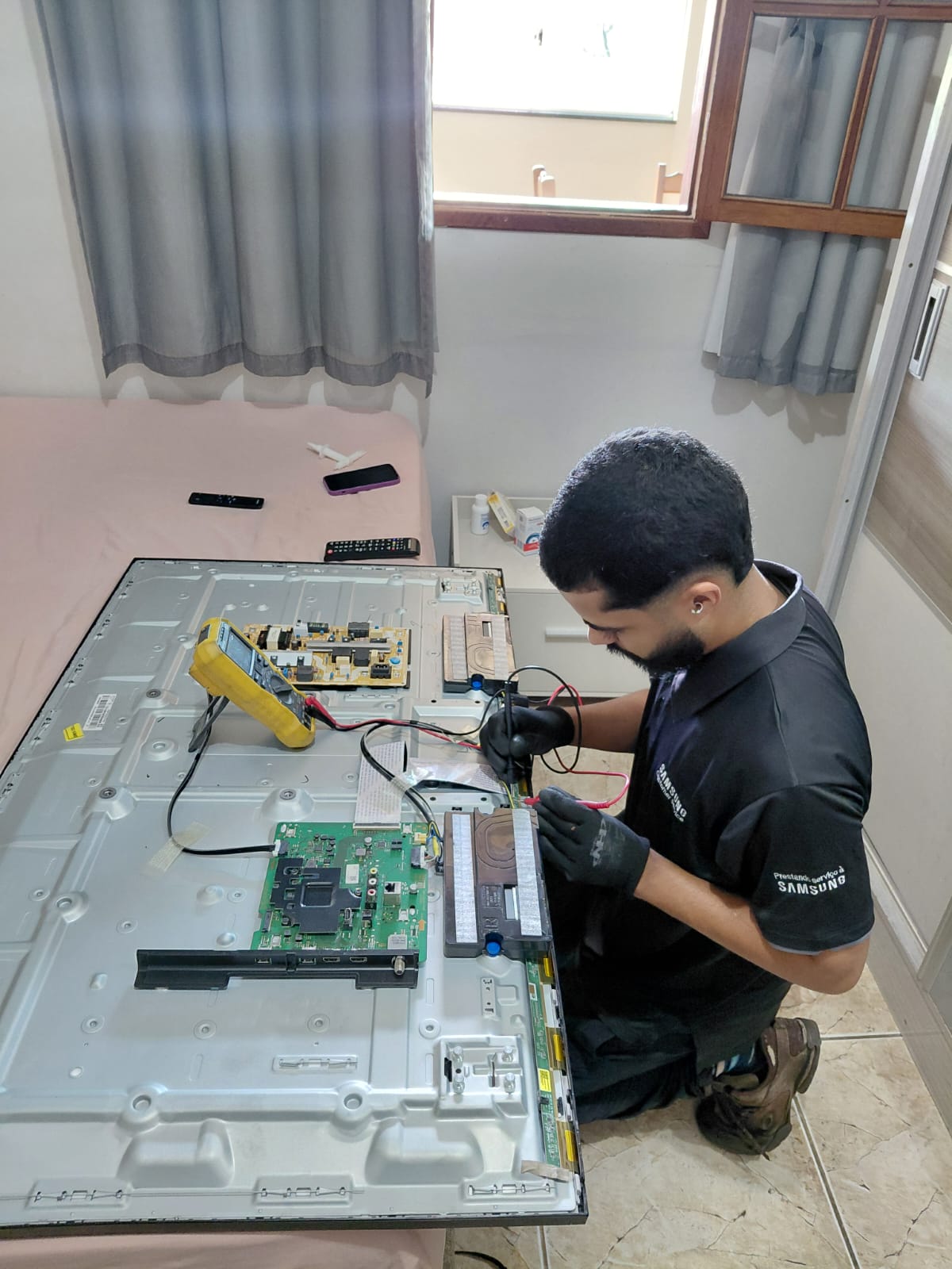 Técnico MinasFast realizando diagnóstico em placa de TV Samsung na casa do cliente